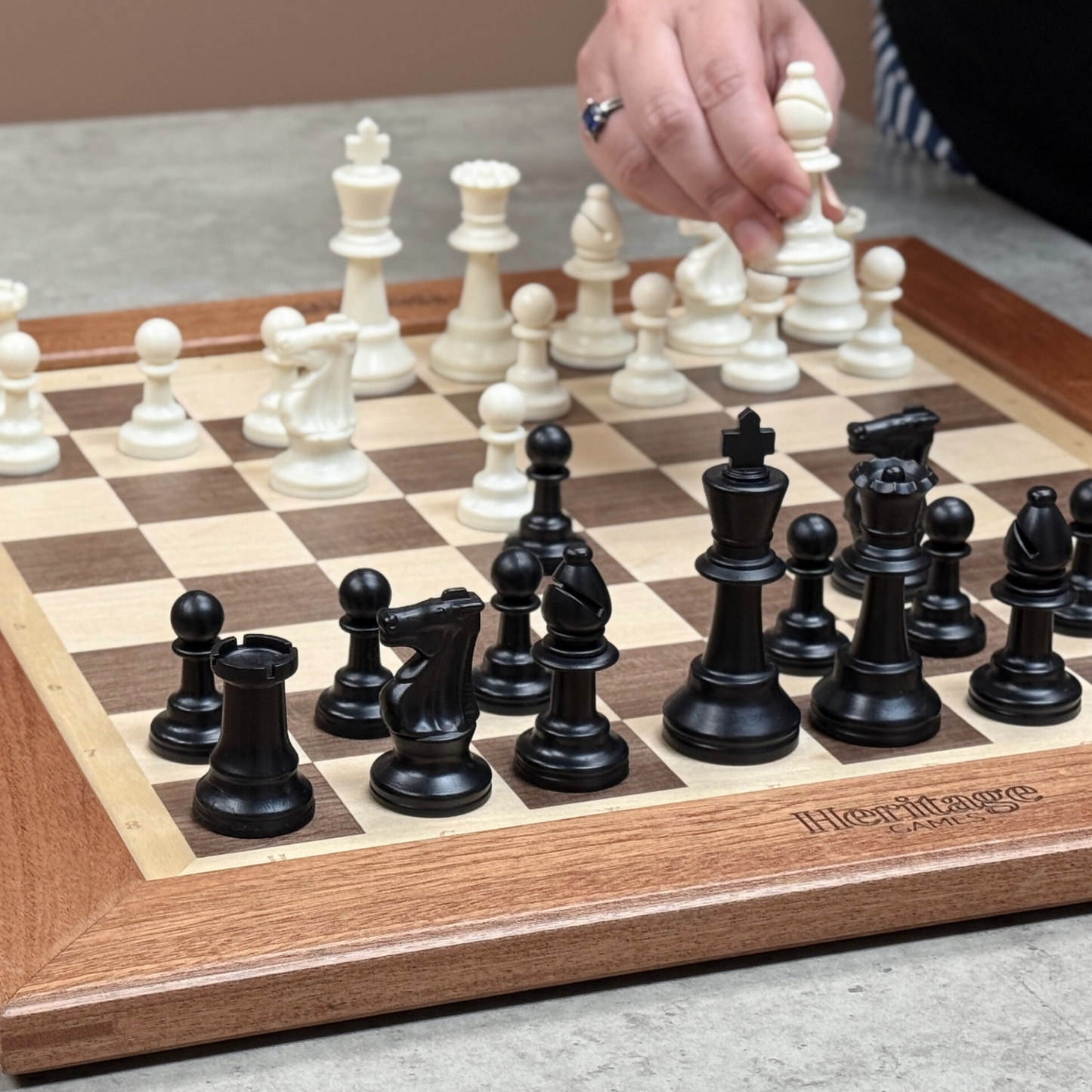 Person playing chess with a wooden board and Heritage pieces.