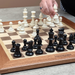 Person playing chess with a wooden board and Heritage pieces.